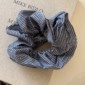 Détail d'un chouchou en tissu à rayures bleues orné de strass brillants et texture