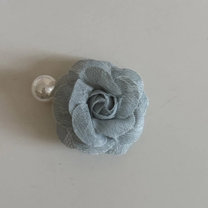 Detailed close-up of blue lace camellia flower hair clip with a large white pearl accent