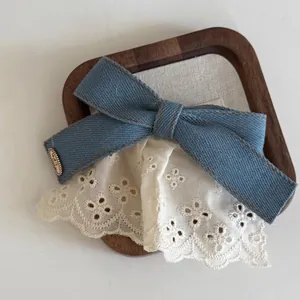 Denim bow hair clip with white lace trim and round metal charm in vintage style