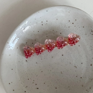 Macro d'une pince à cheveux en acétate rose en forme de cœur avec base dorée et texture neige