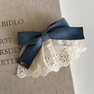 Detail of denim bow hair clip featuring lace trim and a metal tag engraved with Love is Forever