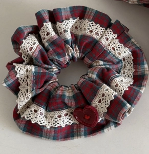 Close-up of retro plaid scrunchie with white crochet lace and red heart button
