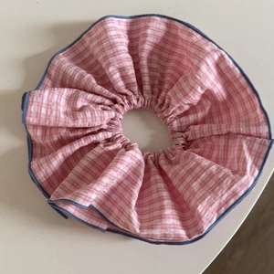 Dettaglio dell'elastico per capelli a quadretti rosa con volant e bordo blu