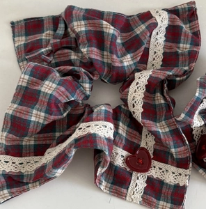 Detailed view of red and green plaid scrunchie with lace edge and heart button