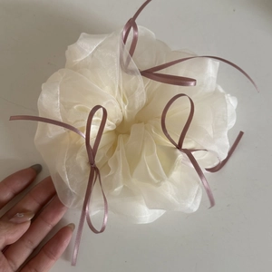 Detail of white organza scrunchie with delicate purple ribbon bows in a macro view