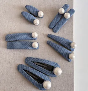 Set of denim fabric hair clips with large white pearls on a grey linen background