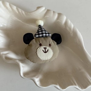 Pince à cheveux ours en peluche avec chapeau de fête à carreaux sur plateau coquillage