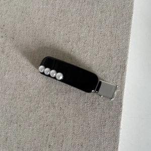 Vue détaillée de quatre perles blanches sur une pince à cheveux noire minimaliste pour le style