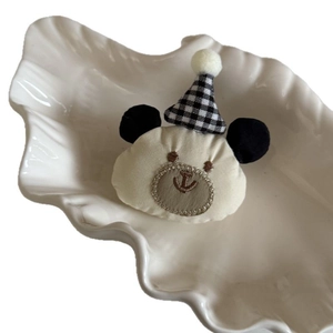 Barrette ours en peluche beige avec bonnet à carreaux noir et blanc sur plateau blanc
