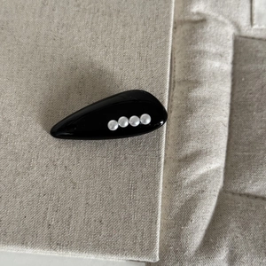 Vue détaillée de la barrette à cheveux en acrylique noir avec quatre perles blanches