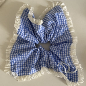 Detail of blue plaid fabric headband featuring white lace trim and pearl bow embellishment