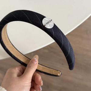 Detail of black striped headband featuring a white Paris button and non-slip inner lining
