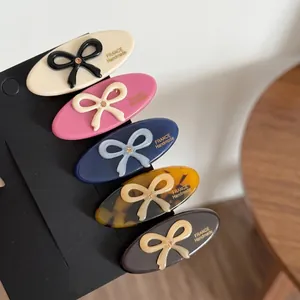 Set of 5 acetate hair clips with bow designs and crystal accents on black card