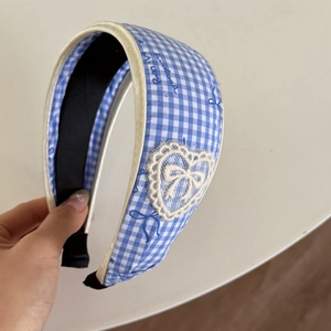 Detail of blue gingham headband featuring white lace heart appliqué and bow patterns