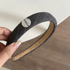 Striped grey wide headband with PARIS button detail shown in a lifestyle hand-held view