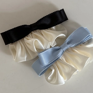 Elegant satin ruffle hair clips with contrasting bow edge detail in black and blue colors