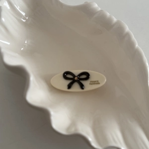 Close-up of an oval acetate hair clip with a black bow and France Handmade text