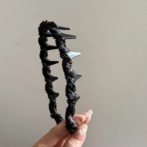 Détail d'un serre-tête en tissu noir tressé avec perles et peigne antidérapant