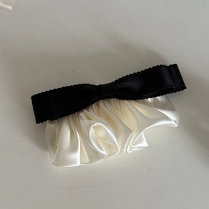 Detail of black grosgrain bow with cream satin pleated ruffles on a vintage hair clip