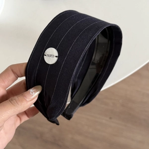Detail of blue striped wide headband featuring a white Paris engraved decorative disc