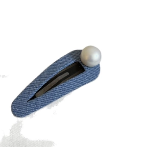 Light blue denim fabric hair clip with white faux pearl decoration on a white background