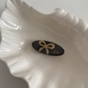 Detail of a black oval acetate clip featuring a bow pattern and France handmade gold logo