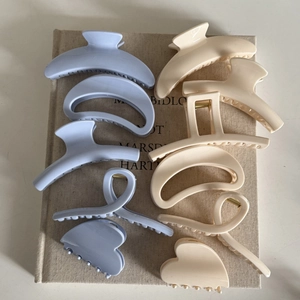 Detailed close-up of light blue and cream matte hair claw clips in various geometric shapes