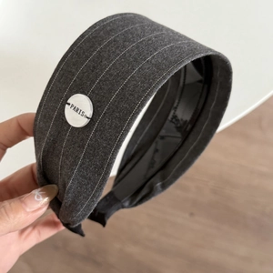 Detail of grey striped fabric headband featuring a white Paris button and soft inner lining