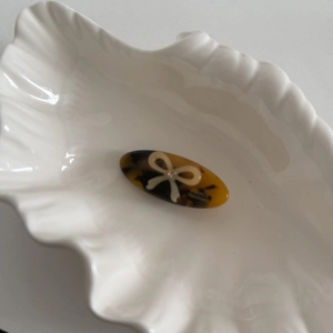 Detailed macro view of tortoiseshell acetate hair clip with white bow and gold lettering