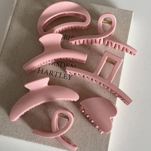 Minimalist creamy pink hair claw clips set elegantly placed on a linen texture book background
