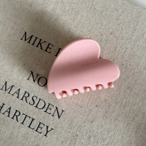 Detailed view of pink heart-shaped hair claw clip with glossy resin finish on linen background