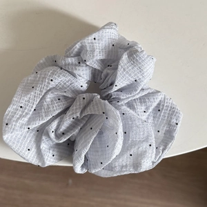 Detailed view of light blue polka dot seersucker scrunchie with wrinkled fabric texture