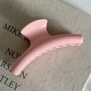 Macro shot of pink glossy hair claw clip showing streamline hook design and inner teeth details