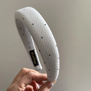 Detailed close-up of a white padded headband with black polka dots and mesh texture