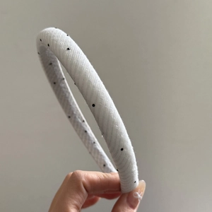 Detailed close-up of retro white mesh headband with black polka dots and sponge padding