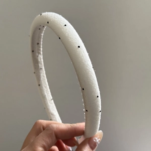 Close-up of white fabric headband with delicate black bead details and woven texture