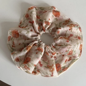 Vue détaillée d'un chouchou en organza à fleurs orange avec des bords cousus fins