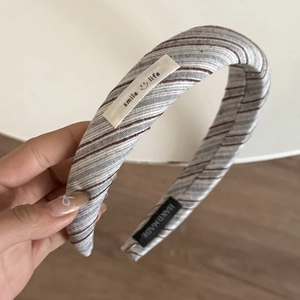 Detail eines grau gestreiften Stoff-Haarreifs mit Handmade-Tag und Smile-Life-Label