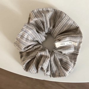 Detail eines gestreiften Haargummis mit Smile Life Etikett und feiner Stoffstruktur