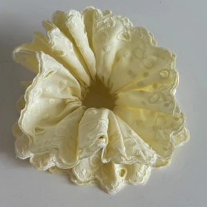 Close-up of cream lace scrunchie with floral embroidery and scalloped edges