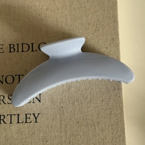 Close-up of the pastel blue shark hair claw clip showing glossy resin texture and teeth