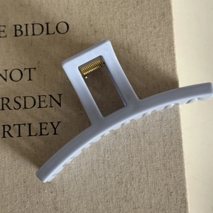 Detail of matte cream blue square hair claw clip with golden metal spring and hollow design