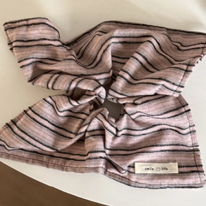 Detailstruktur eines rosa-schwarz gestreiften Scrunchies mit Smile Life Textiletikett