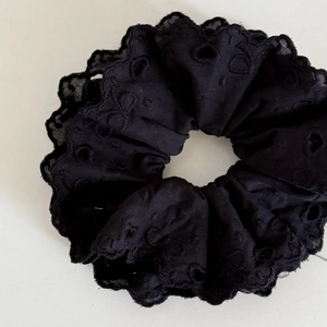 Detailed view of black lace scrunchie with layered hollow embroidery and ruffled edges