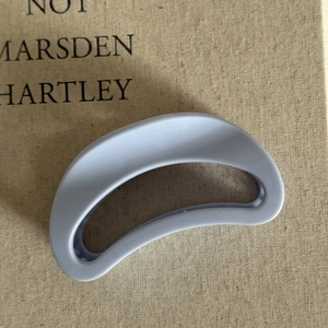Minimalist matte cream blue hair claw clip for women on a textured book surface
