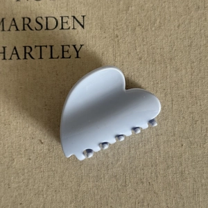 Macro detail of heart-shaped cream blue hair claw clip on neutral linen texture