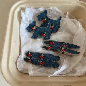 Macro detail of denim cherry hair clips with red rhinestones in a gift box