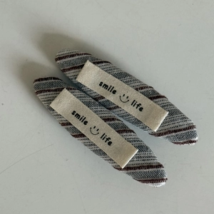Nahaufnahme von gestreiften BB-Haarklammern aus Stoff mit Smile-Life-Textiletikett