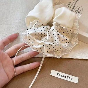 Detailed close-up of polka dot scrunchie with lace edges and a long ribbon bow
