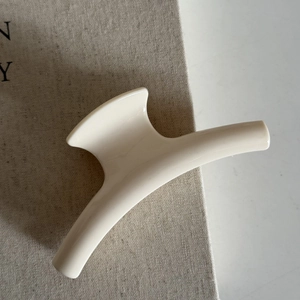 Close-up of cream white glossy hair claw clip on beige textured fabric background